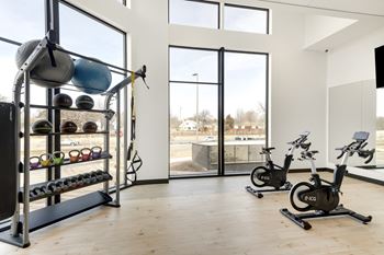 A gym with a row of exercise bikes and a rack of kettlebells. at Zelia on Seven, St Louis Park, MN, 55416